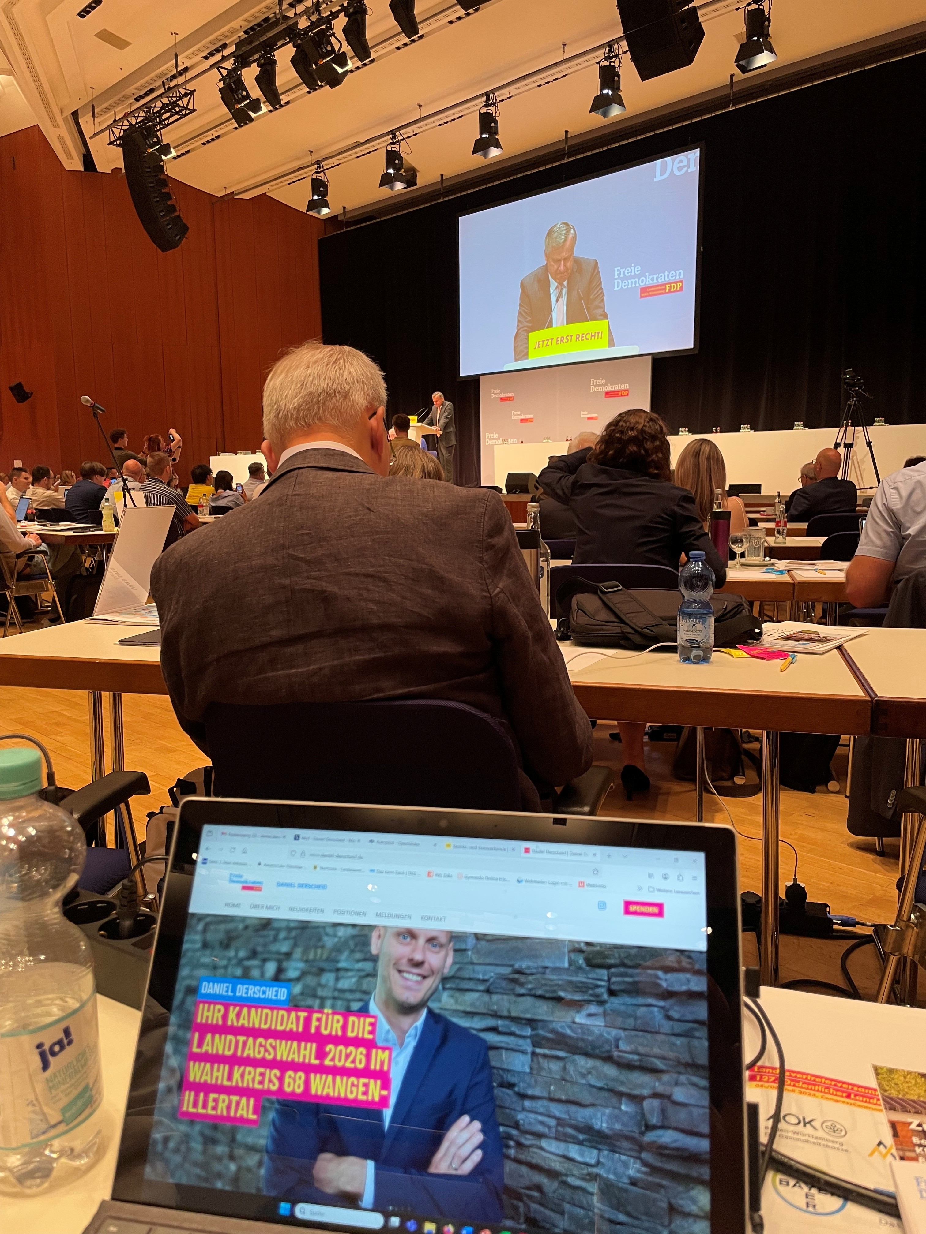 Ein Foto vom Platz mit Blick zur Leinwand während der Rede von Herrn Ruelke. Man sieht im vordergrund den Laptop mit der Kandidatenhomepage von Daniel Derscheid