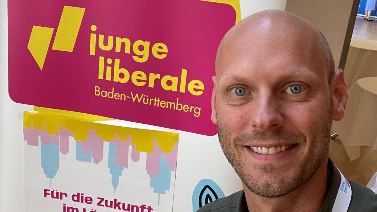 Daniel Derscheid vor einem Banner der Jungen Liberalen