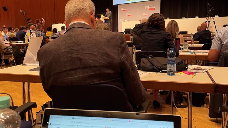 Ein Foto vom Platz mit Blick zur Leinwand während der Rede von Herrn Ruelke. Man sieht im vordergrund den Laptop mit der Kandidatenhomepage von Daniel Derscheid